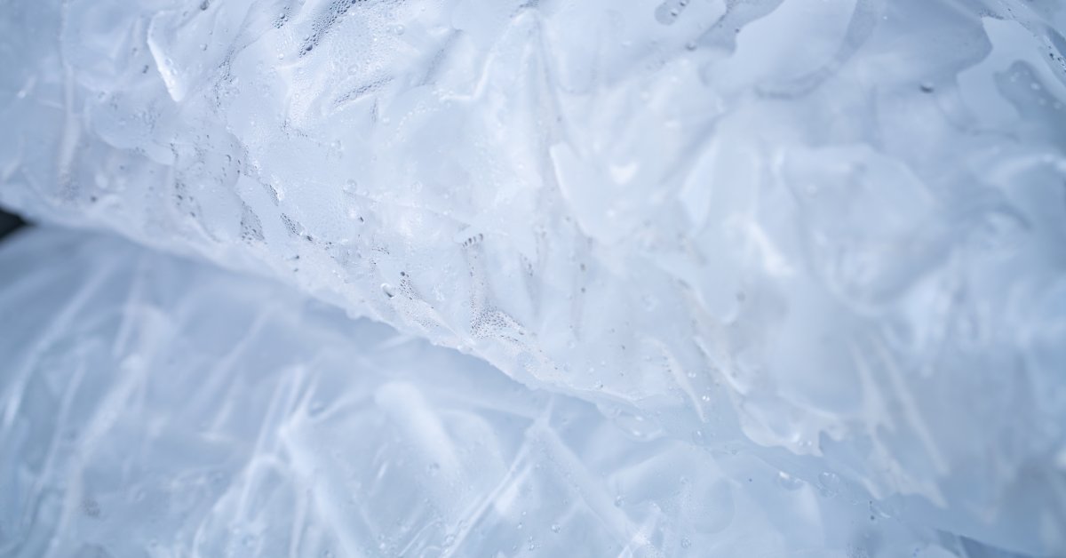 A close-up of bagged ice on top of another bag. The bags are clear with condensation on the sides.