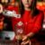 A woman stands behind a bar with a glass in front of her. She uses a metal scoop to pour ice into a glass.