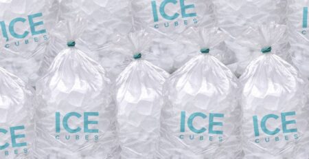 Several large bags of ice rest on top of each other. The front of the bags says "ICE CUBES" in blue font.