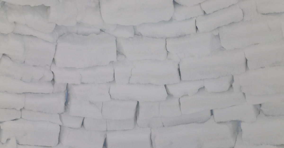 A wall of snow/ice blocks stacked on top of each other. Each chunk is cut in varying sizes with cracks between pieces.