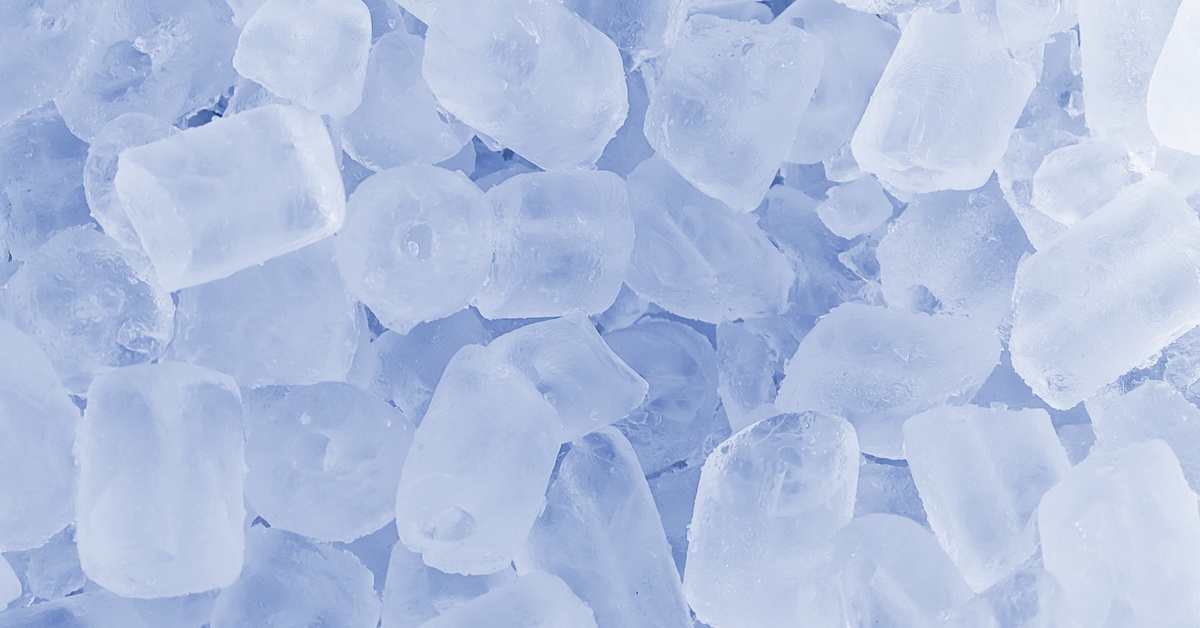 A close-up pile of translucent ice cubes, frosty and slightly rounded, with a hole in the middle.