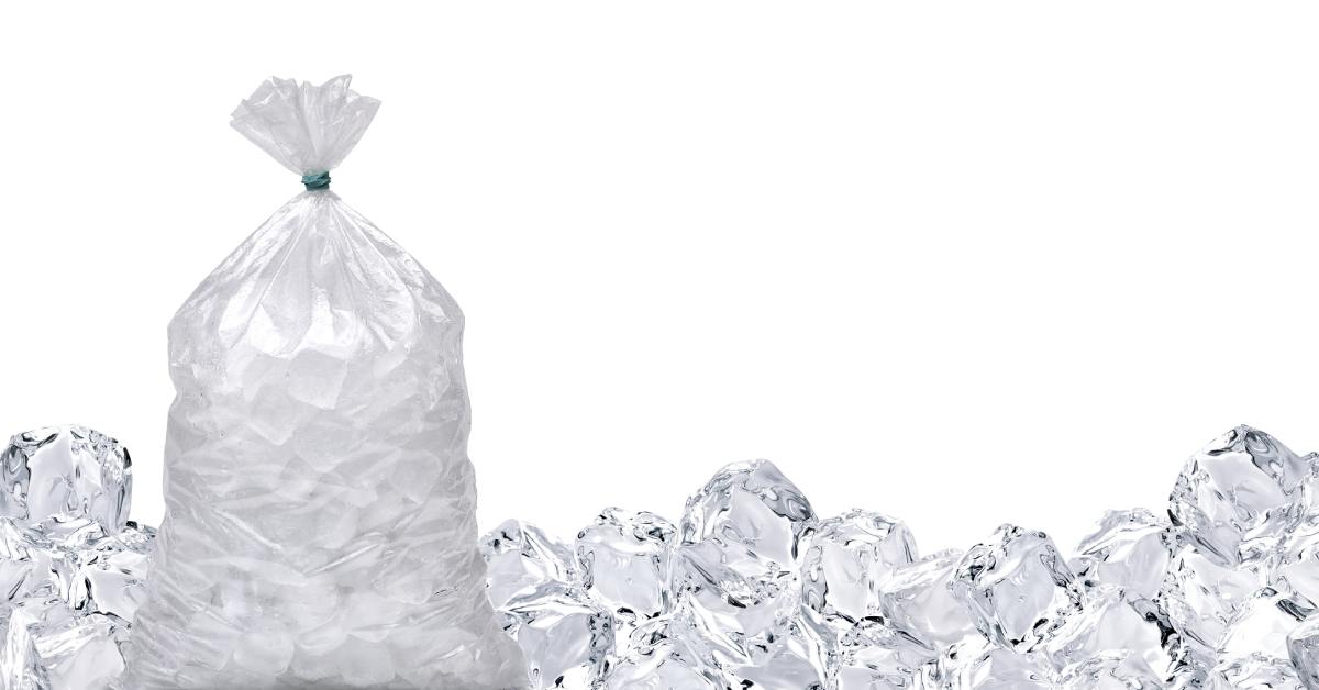 Clear ice cubes packed in a sealed plastic bag on a white background. Extra ice cubes line the bottom of the frame.