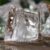 Several clear ice cubes melt on a wet surface as warm outdoor air softens their edges and forms small puddles.