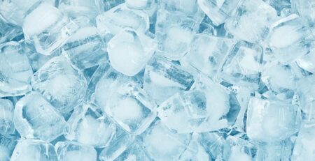 A close arrangement of clear ice cubes filling the space with light blue tones and frosty textures across the surface.